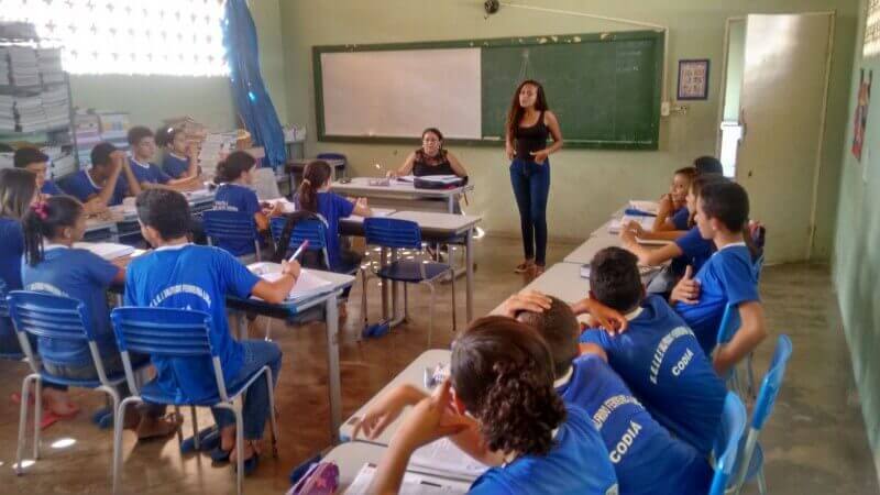 Menina discursando em frente aos alunos em uma sala de aula